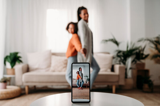 Mother and daughter filming video through smart phone at home