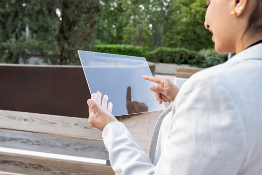 Female professional using transparent glass tablet at park