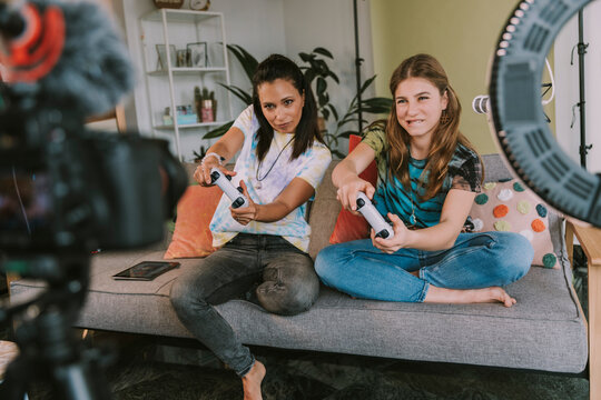 Concentrated female gamers playing video game while vlogging at home