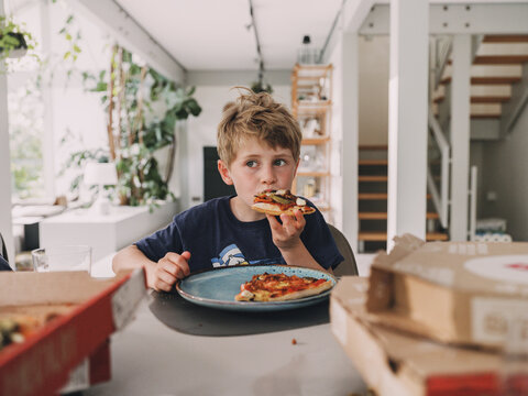 Child eating a slice of pizza for dinner at home