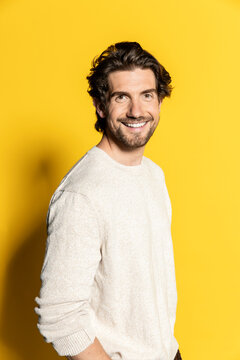 Handsome businessman smiling on yellow background