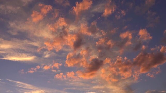 Dramatic Fiery Sunset Clouds Across the Sky with Vibrant Orange and Blue Cloudscape Over a Serene Natural Landscape