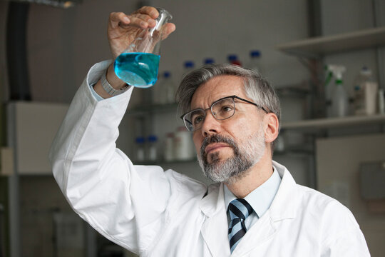 Scientist in laboratory examining liquid in Erlenmeyer flask