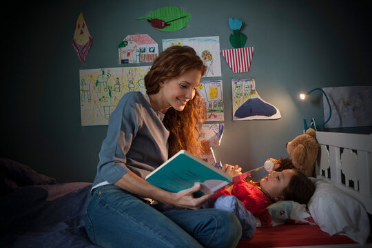 Mother reading a bedtime story for her little daughter