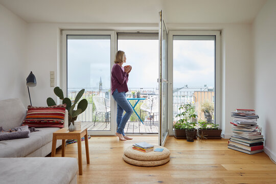 Mature woman at home looking out of balcony window
