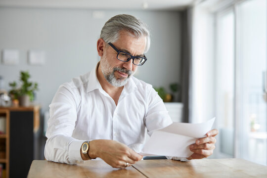 Portrait of mature man reading letter at home