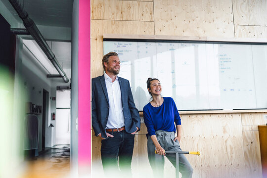 Mature man and his assistent with scooter, standing in office in front of white board