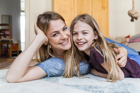 Portrait of happy little girl lying on the floor with her mother