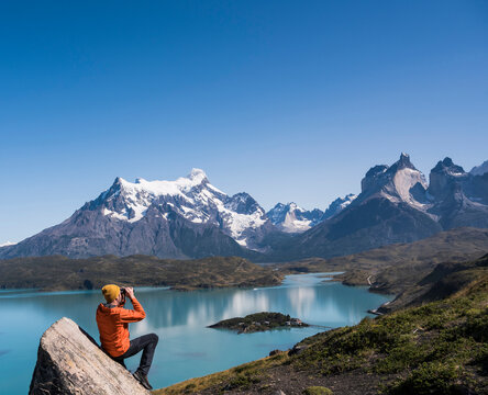 Hiker looking through binocular at Torres del Paine and Lago Pehoe