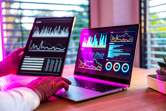 Man analyzing financial data on notebook and tablet in the office