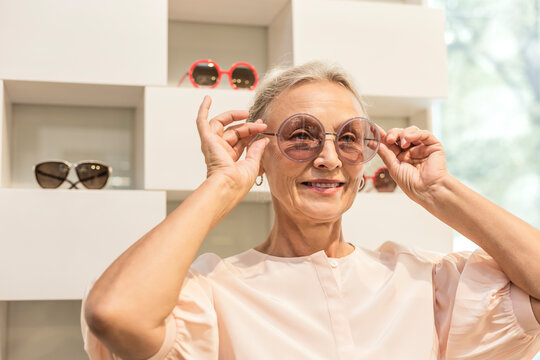 Smiling senior woman trying on sunglasses in a boutique