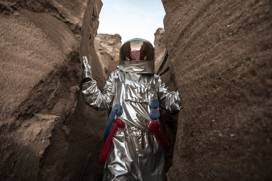 Spaceman exploring nameless planet, examining canyon