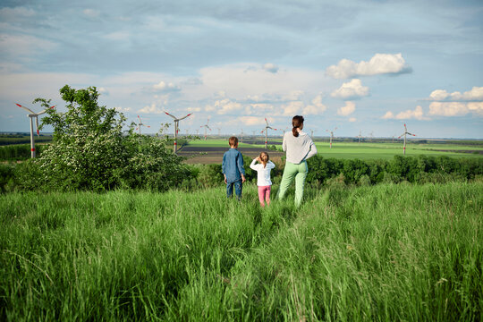 Mother with son and daughter looking at windwheels on field