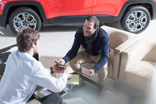 Man at car dealership looking at brochure
