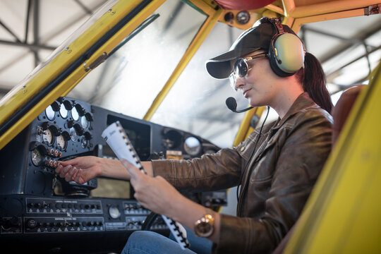 Female pilot inspecting light aircraft cockpit