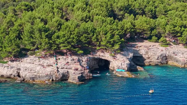 Aerial drone footage revealing famous shoreline of Galebove stijene near Pula, Croatia. Popular summer destination for swimming, cliff jumping, kayaking, and coastal exploration