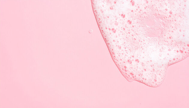 Soap foam texture on pink background, shampoo bubbles, hygiene and bath care concept. Close-up.