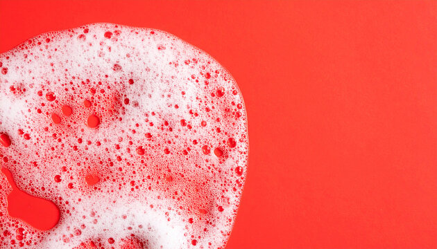 Soap foam texture on red background, shampoo bubbles, hygiene and bath care concept. Close-up.