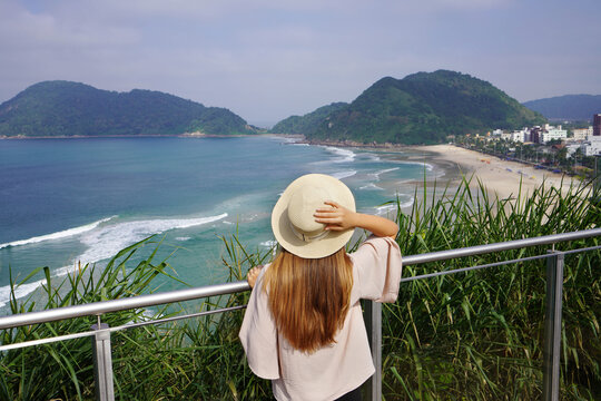 Backview of young woman enjoying view of Praia do Tombo beach in Guaruja, Baixada Santista, Brazil