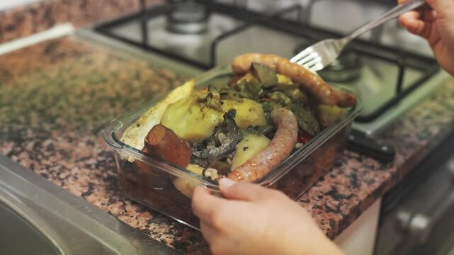 Unrecognizable person using a fork to stir a homemade meal of butifarra and vegetables