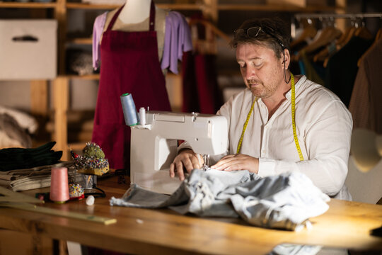 Middle-aged male dressmaker working with sewing-machine