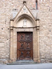 Ancient Romanesque Gothic church wooden door with stone arch portal and marble Madonna sculpture in Florence Italy © BlackMac