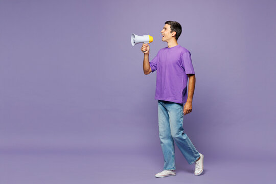 Full body young man he wears violet t-shirt casual clothes hold in hand megaphone scream announces discounts sale Hurry up isolated on plain pastel light purple background studio. Lifestyle concept.