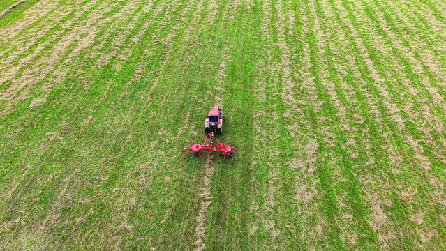 Tractor cultivating green field using a rotary tiller for soil preparation and farming tasks