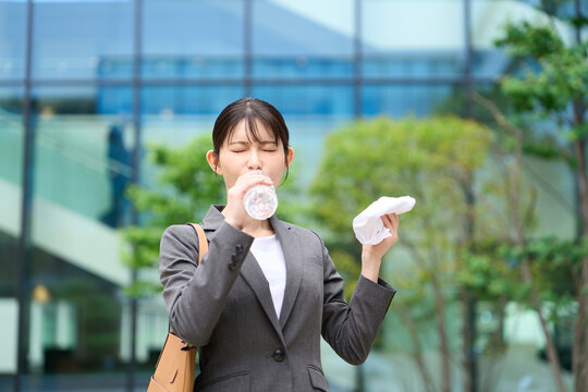 暑い屋外で水を飲むビジネスウーマン