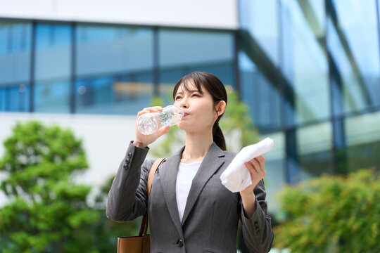 暑い屋外で水を飲むビジネスウーマン