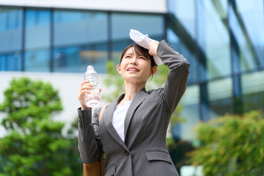 暑い屋外で汗を拭くビジネスウーマン