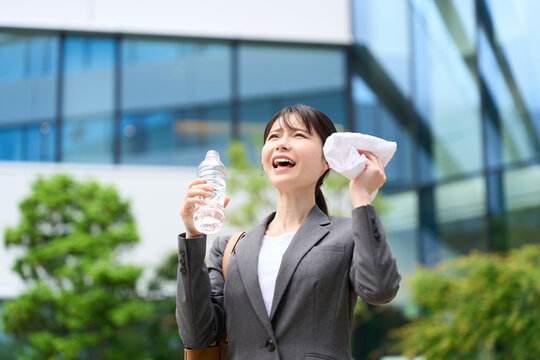 暑い屋外で水を飲むビジネスウーマン