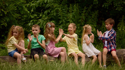 Fototapeta premium Children enjoying interactive hand clapping game together in park. Concept of friendship, emotional wellbeing, positive childhood experiences, and playful learning.