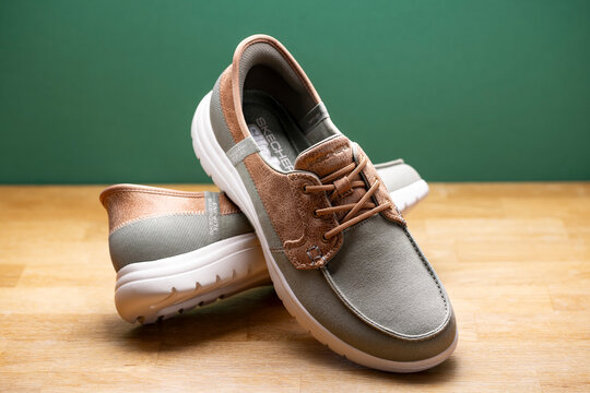 Skechers Slip-ins casual shoes displayed on wooden table with green background &ndash; editorial product photography