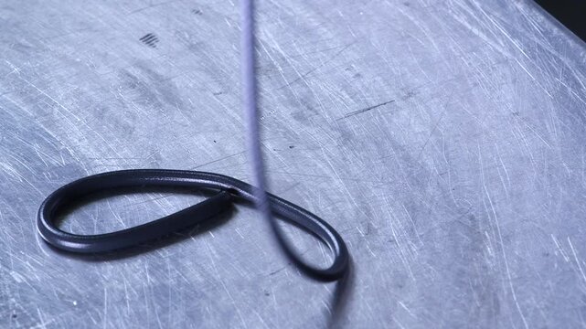 Close-up of a polymer filament emerging from industrial equipment during an extrusion process. Ideal for manufacturing, plastics engineering and industrial production concepts.