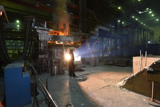 Workers in protective equipment in a foundry during the production of steel components - workplace industrial factory