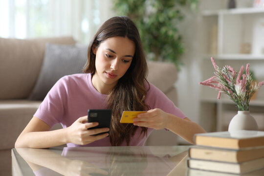 Serious woman reading card number buying online with a phone