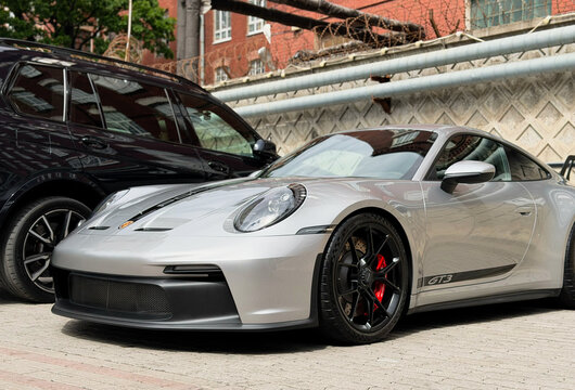 Porsche 911 RS GT3 silver sports car parked on parking lot. Silver sport coupe Porsche 991 GT3 RS on parking lot. Luxury German sport coupe car Porsche 911 GT3 with a large spoiler.