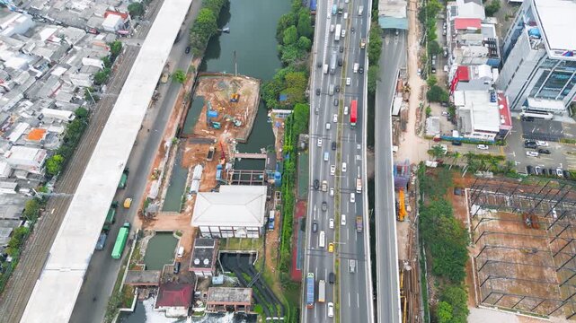 Aerial View of Urban Infrastructure Construction Site and Highway Traffic next to River Canal