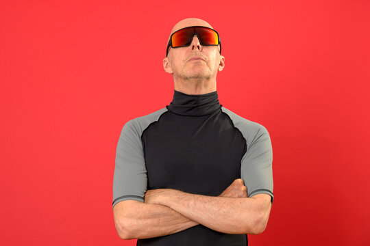 sporty bald man standing with arms folded, looking up