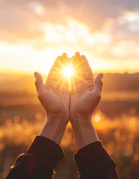 Manos elevadas hacia la luz del sol de amanecer en un paisaje c&aacute;lido y sereno. Simbolo de oraci&oacute;n, esperanza, fe, gratitud, confianza y paz interior