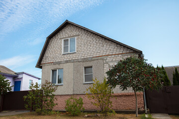 Obraz premium A house with a tree in front of it. The house is made of bricks. There are two windows on the front of the house