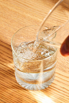 Pouring Fresh Clean Water into a Glass on a Wooden Table