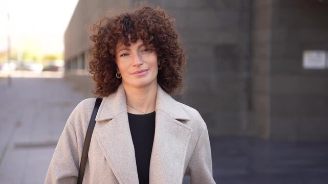 A Stylish Young Woman with Curly Hair Captured in a Modern Urban Setting on a Beautiful Day