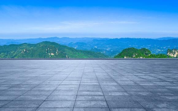 Empty plaza overlooking green mountain range under blue sky in China