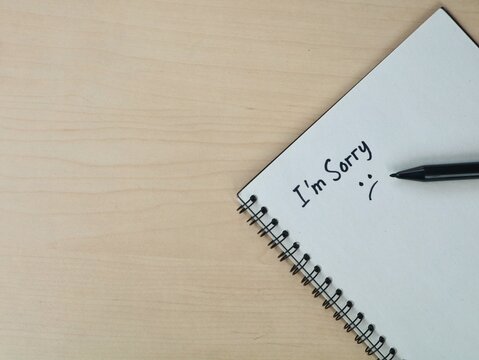 I am sorry text handwritten on book on wooden desk background with copy space. Making it ideal for concepts related to apology, regret, relationship issues, forgiveness, and emotional confessions