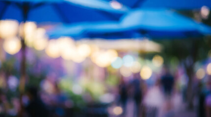 Obraz premium Blurred outdoor cafe background with blue umbrellas, soft bokeh lights on a summer terrace, out of focus restaurant patio scene