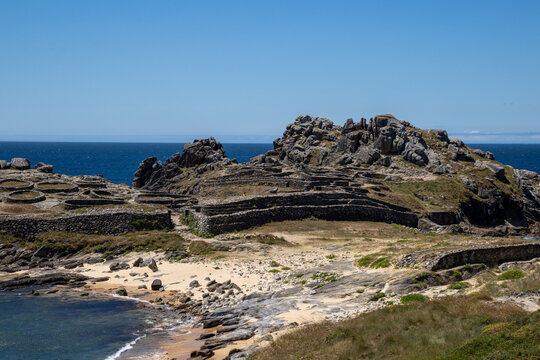 Prehistoric Celtic ruins of Castro de Baro&ntilde;a in Porto do Son, Galicia, Spain. Ancient Iron Age circular stone houses and fort fortress on a rocky coast peninsula facing the blue Atlantic Ocean.