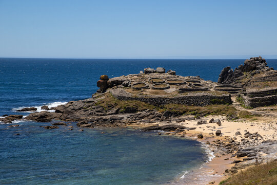 Prehistoric Celtic ruins of Castro de Baro&ntilde;a in Porto do Son, Galicia, Spain. Ancient Iron Age circular stone houses and fort fortress on a rocky coast peninsula facing the blue Atlantic Ocean.