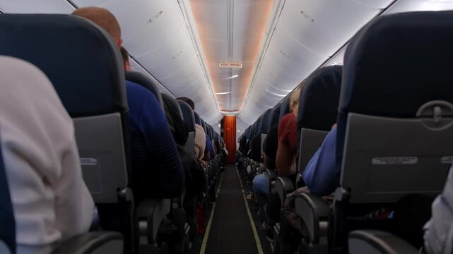 Interior view of crowded commercial airplane cabin with passengers sitting in their seats during flight